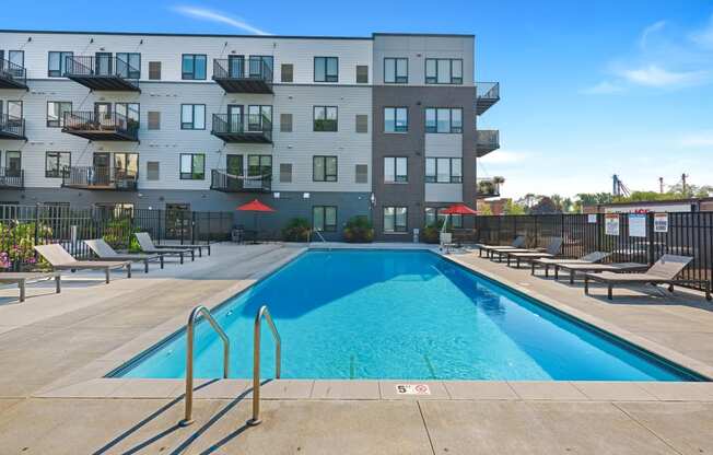 an apartment complex with a swimming pool and chaise lounge chairs