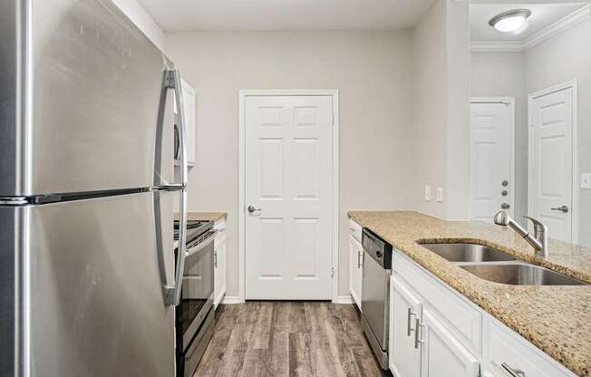A kitchen with a stainless steel refrigerator and white cabinets.