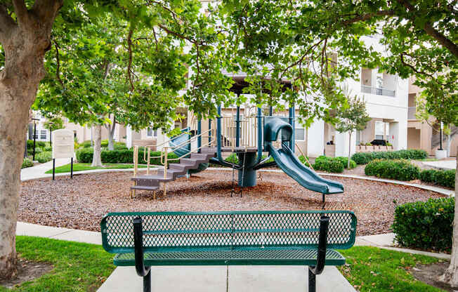 A playground with a green slide and a bench.