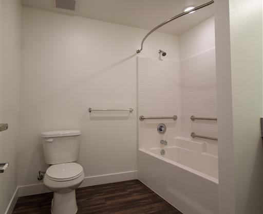 a white toilet sitting next to a bath tub at Loma Villas Apartments, San Bernardino, 92408