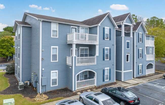 a blue apartment building with cars parked in a parking lot
