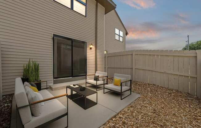 a patio with couches and chairs in front of a house