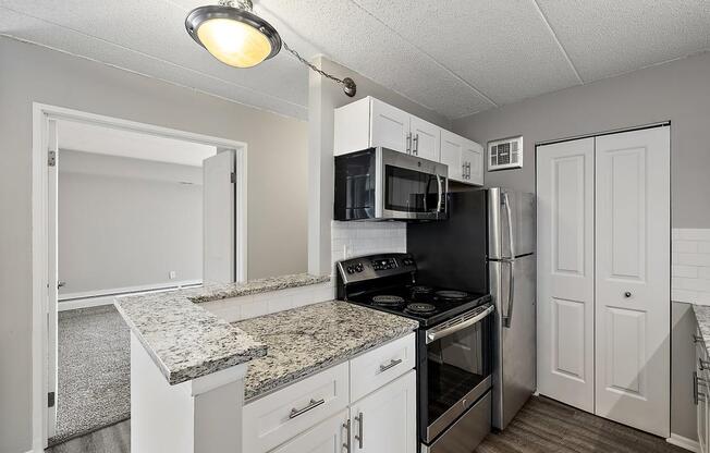 a kitchen with granite counter tops and black appliances with ceiling light at Troy Place Apartments - Troy, MI, Troy