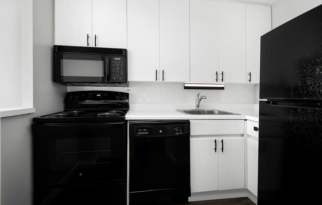A black and white photo of a kitchen with white cabinets.