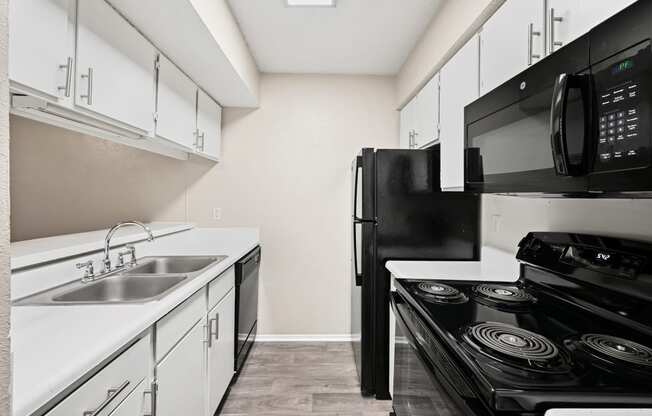 a kitchen with white cabinets and black appliances