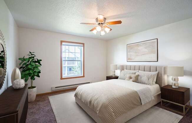 A bedroom with a large bed and a ceiling fan. Fargo, ND Stonebridge Apartments