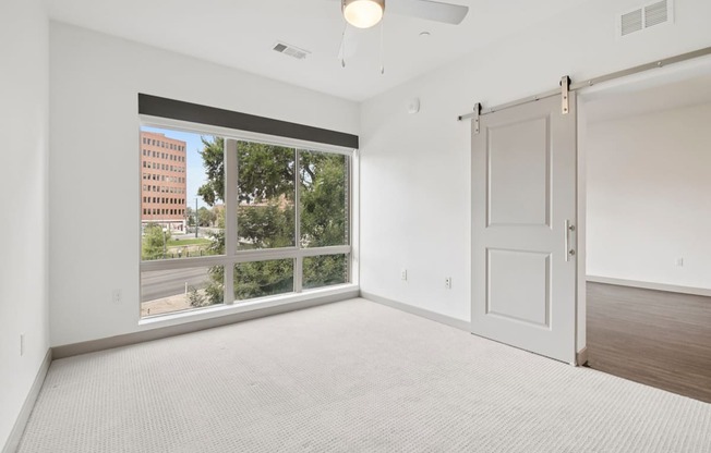 A spacious room with a large window and a sliding door.