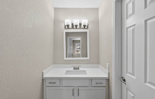 A white bathroom with a sink and mirror.