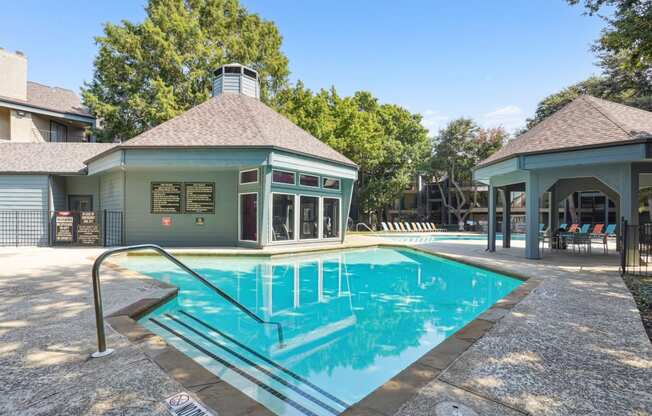 Sparkling swimming pool surrounded by a lush green lawn at Laurels of Sendera apartments in Arlington, TX