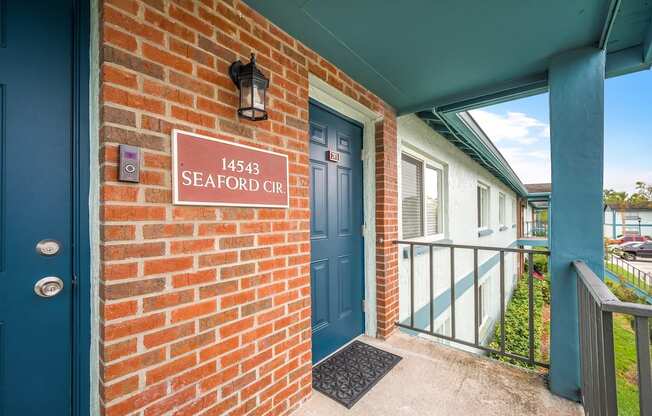 the entrance to a red brick building with a blue door and a sign that reads