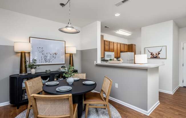 a dining area with a table and chairs and a kitchen in the background
