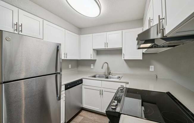 A kitchen with a stainless steel refrigerator and black countertops.