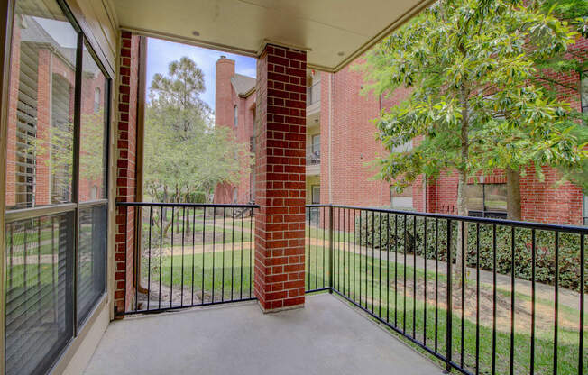 a balcony with a black railing and a brick building in the background