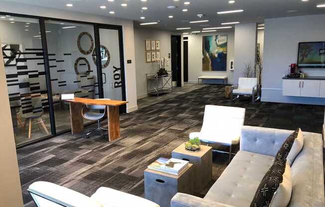 A modern community room with a grey couch and a wooden coffee table.