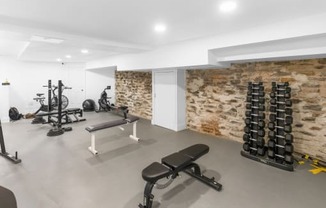 a workout room with weights and a stone wall