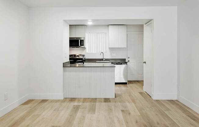 A kitchen with white cabinets and a wooden floor.