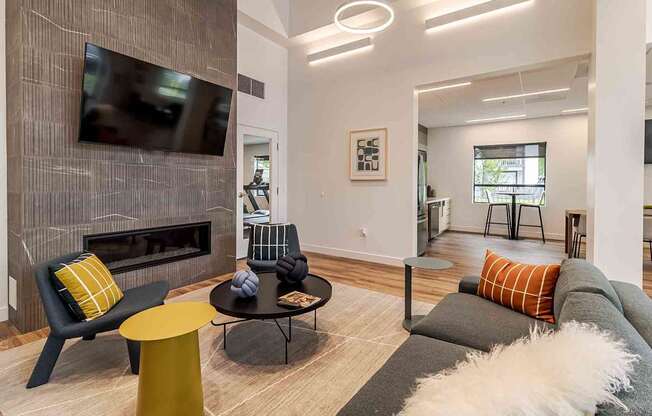 A modern living room with a grey couch, a yellow chair, and a fireplace.