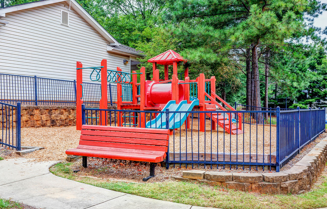 View of Playground, Showing Fenced-In Area, Monkey Bars, and Bench at Summer Park Apartments