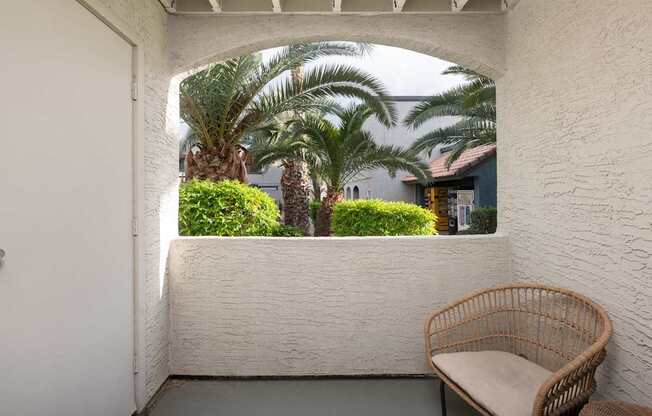 a balcony with a chair and palm trees