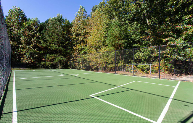 a tennis court with trees in the background on a sunny day