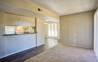 an empty living room with a kitchen and a counter top