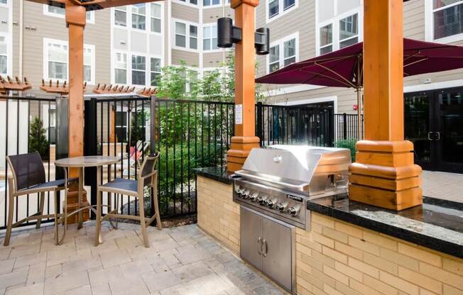 a patio with a grill and a table with chairs