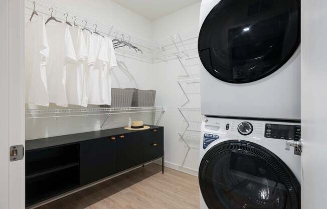 A washing machine is in a laundry room with a dryer in the background.