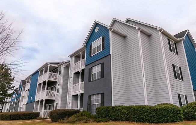 a group of apartment buildings with blue and gray siding