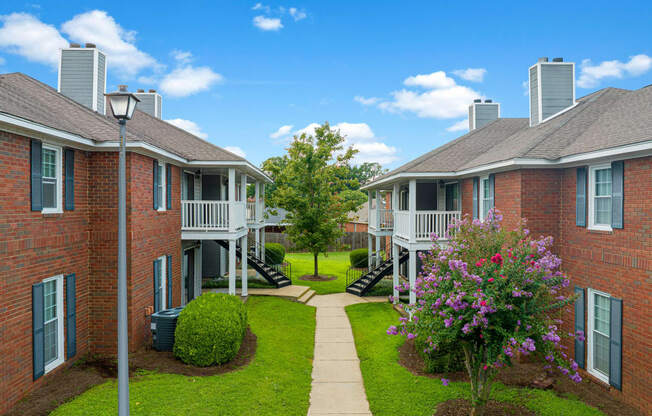 an image of an apartment complex with a walkway and grass