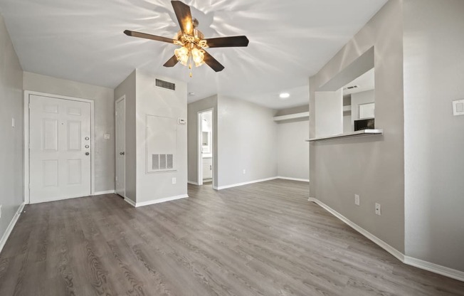 an empty living room with a ceiling fan