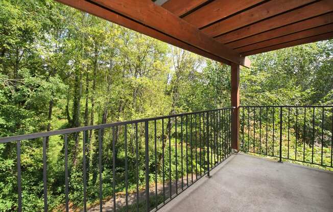 the balcony has a view of the woods and the yard