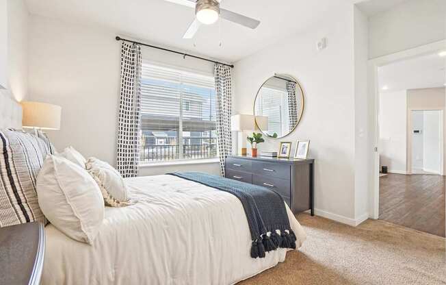 A bedroom with a bed, nightstand, and a window with a view of a balcony. at Connect at First Creek Apartments, Denver, CO