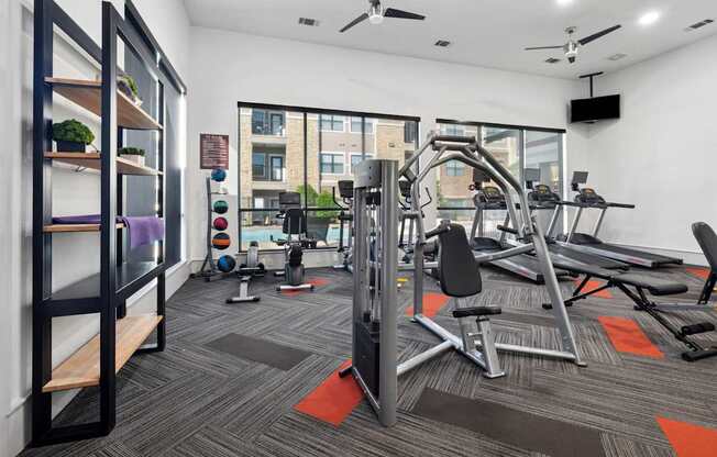 A gym with a variety of equipment including a treadmill, weights, and a bench press.