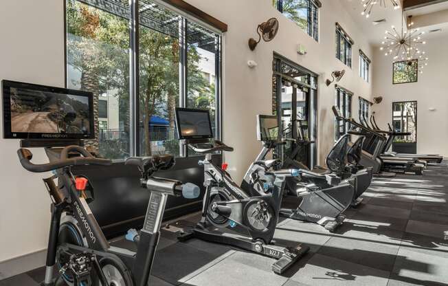 a gym with treadmills and other exercise equipment in a building with large windows