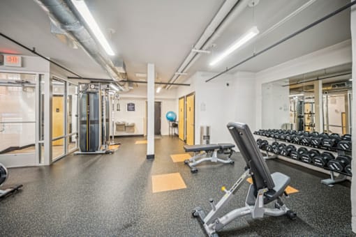 A gym with a variety of equipment including weights and a bench.