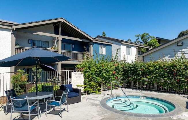 A hot tub with a table and chairs and umbrella.