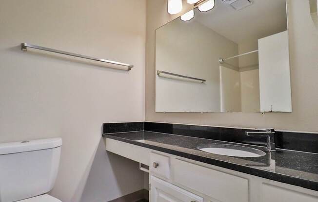 A bathroom with a toilet, sink, and mirror.