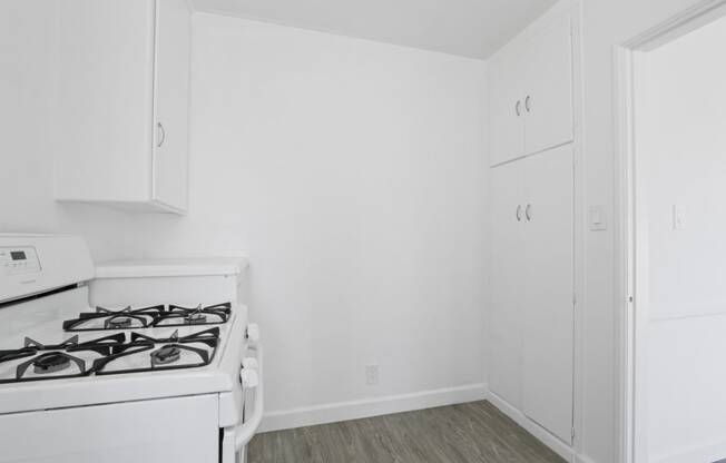 the living room of an apartment with a stove and white cabinets