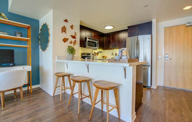 A kitchen with a white counter and wooden stools.