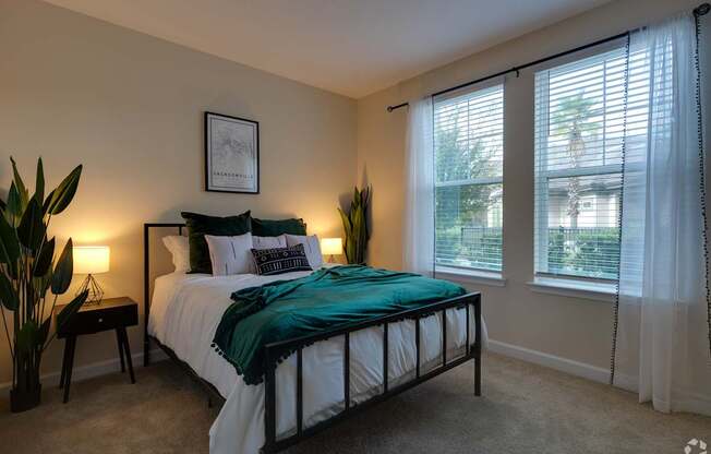 A bedroom with a bed, nightstands, and a window with blinds.