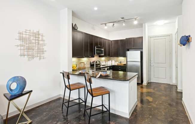 Model kitchen with a counter top with stools at Harlow River Oaks in Houston, TX