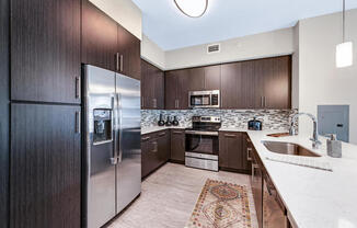 Kitchens with quartz countertops, stainless steel appliances, undermount sinks and 42" wall cabinets