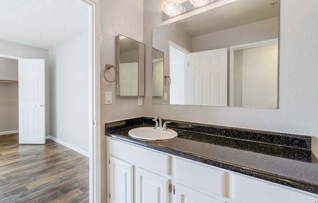 A bathroom with a sink, mirror, and wooden floors.
