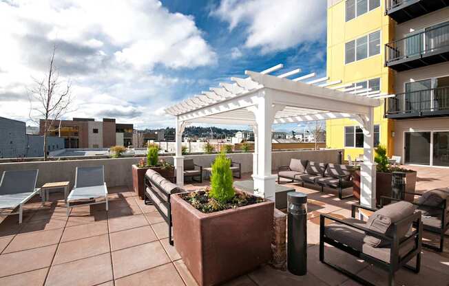A patio with a white pergola and furniture.