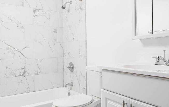 A white toilet in a bathroom with a marble wall.