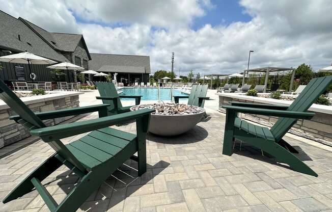 a patio with green picnic tables and a swimming pool at The Depot in Raymore, MO 64083