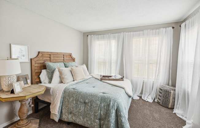 a bedroom with a bed and windows with white curtains