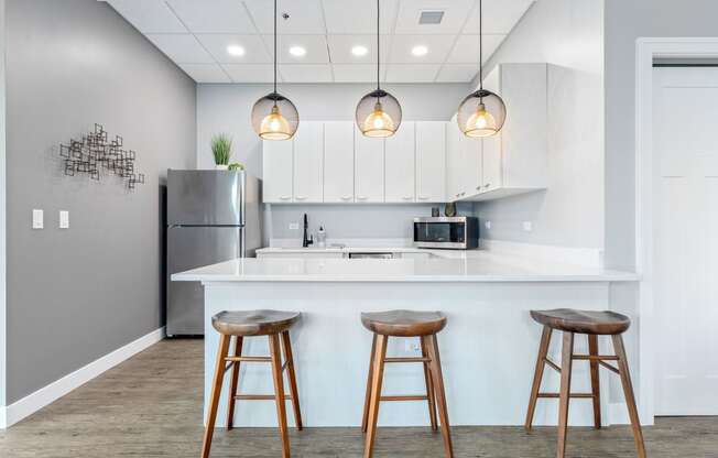a kitchen with white cabinetry and a large white island with three wooden stools