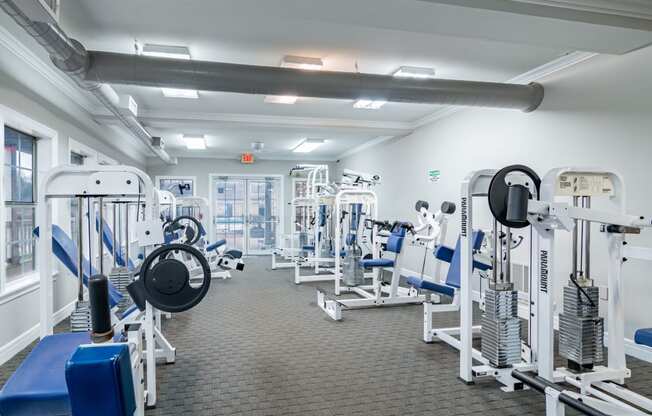 a spacious fitness room with cardio equipment and weights