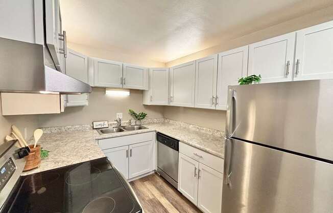 A kitchen with a black stove top oven and a stainless steel refrigerator.
